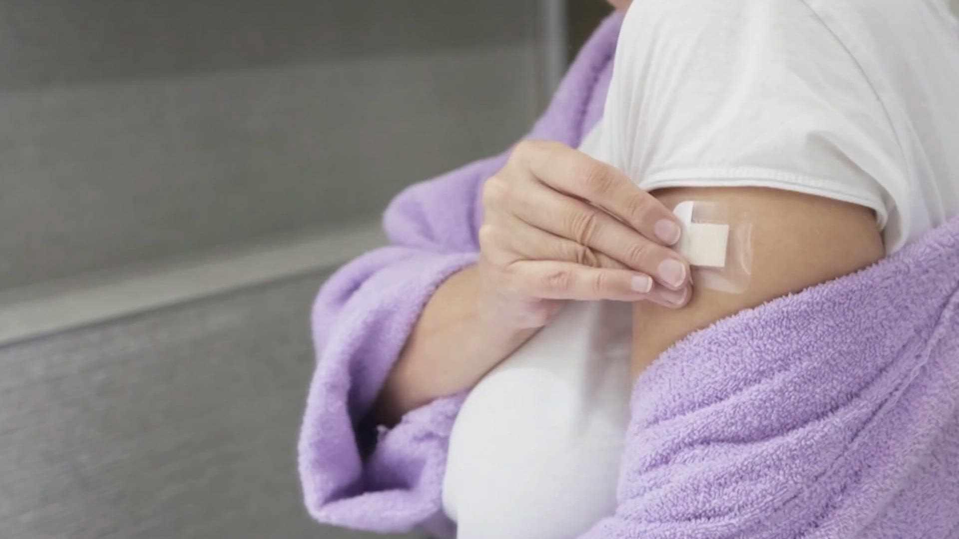 Close up of a woman placing a Hormone Replacement Therapy patch on her arm